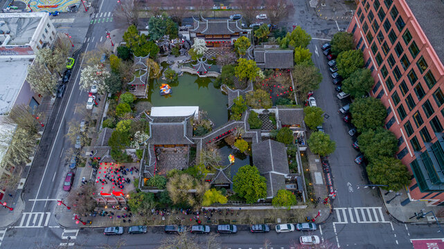 Aerial view of Lan Su Chinese Garden featuring traditional pavilions, a central pond, and lush greenery surrounded by urban streets in Portland, Oregon, United States.