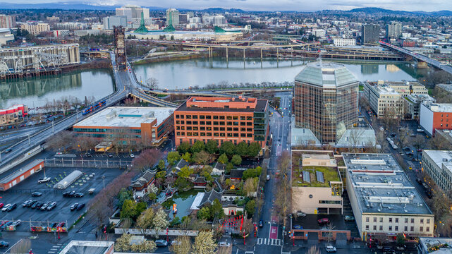 Aerial view of the Lan Su Chinese Garden nestled among urban buildings with the Willamette River and Steel Bridge in the background Portland, Oregon, United States.
