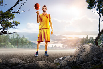 Basketball. A basketball player practices on a basketball court in the wilderness. A beautiful landscape is in the background. © 103tnn