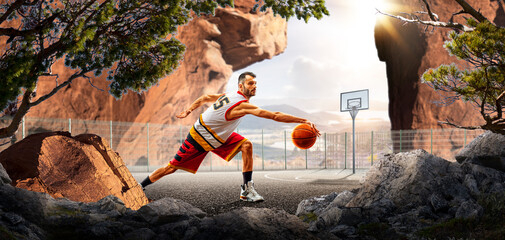 Basketball. A basketball player practices on a basketball court in the wilderness. A beautiful landscape is in the background. © 103tnn