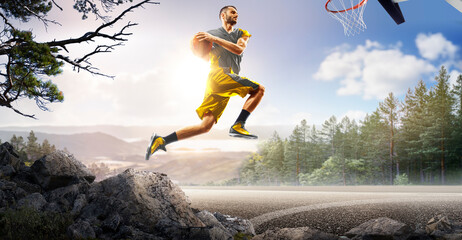 Basketball. A basketball player practices on a basketball court in the wilderness. A beautiful landscape is in the background. © 103tnn