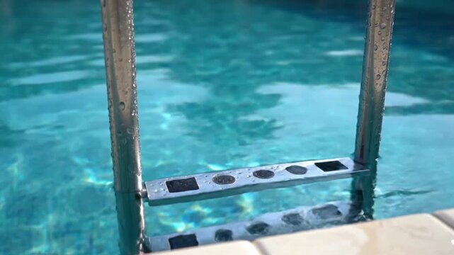 A series of video frames capturing a metal pool ladder leading into a bright blue swimming pool with clear water