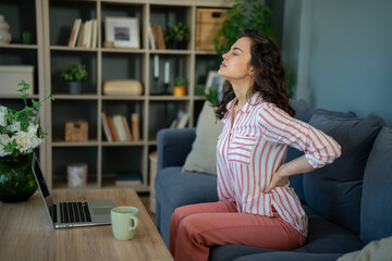 Obraz premium Woman experiencing lower back pain sitting on couch