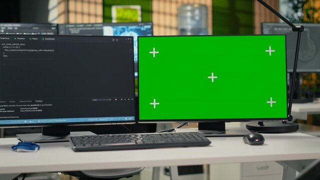 Green screen PC in empty startup office with programming language script running on monitors. Mockup computers in AI industry startup workspace leveraging coding software enhancing system automation