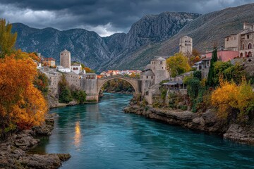 Fototapeta premium Medieval Bridge Over Turquoise River in Autumnal Mountain Town