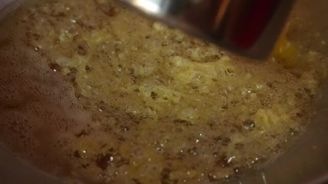 Indonesian egg rolls fried in hot oil, a crispy rolled street food with a puffy golden texture, seen up close.