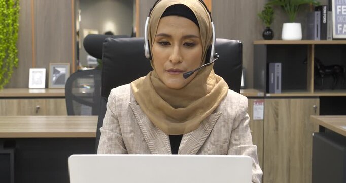 Muslim Women helpdesk call center use headphones talk to customer. Asian woman operator assistant customer service agent. Muslim Islam Businesswoman use laptop computer video call online meeting
