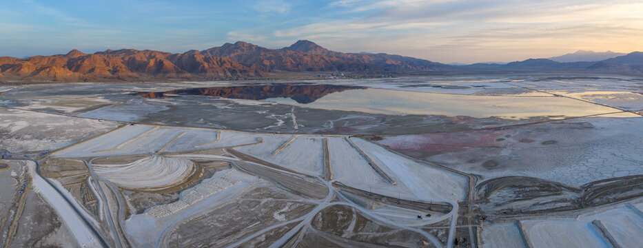 Aerial view of Searles Lake featuring salt crusts, evaporation ponds, and the Argus Range mountains under a soft evening sky San Bernardino County, California, United States.