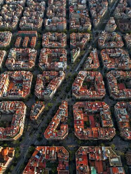 Aerial view of the unique octagonal city blocks and grid layout of the Eixample district with red rooftops and narrow streets in Barcelona, Catalonia, Spain.