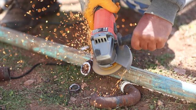 Man is cutting a metal list by angle grinder saw.