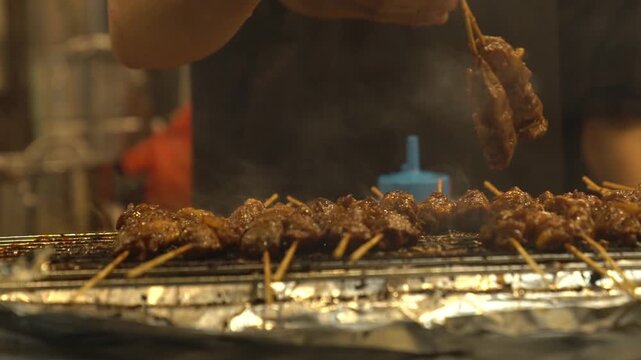 Honey grilled pork satay on a smoky barbecue, authentic Indonesian street food skewers cooked over open flame.