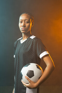 African American woman player holding b and w ball at hip in black kit white-trim studio-lit teal am