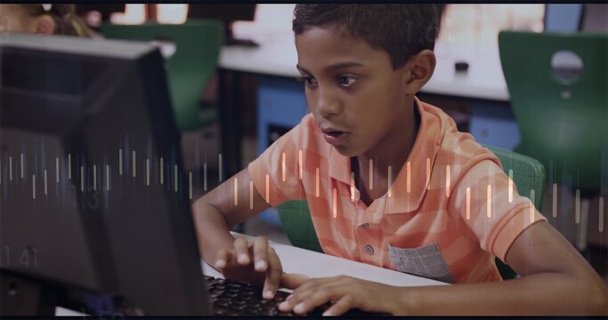 Typing schoolboy wearing orange striped polo leaning toward monitor in computer lab, with waveform