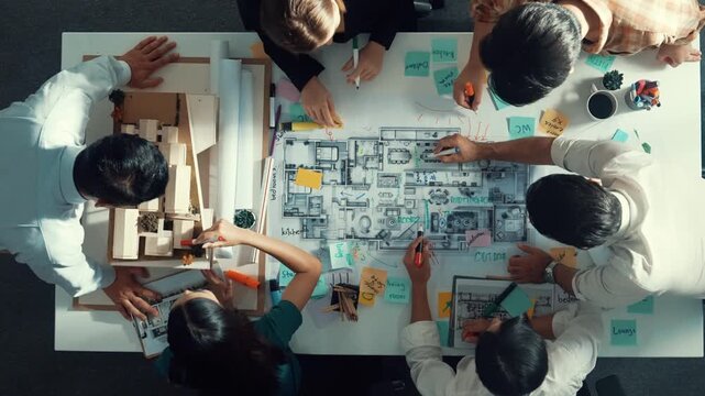 Top aerial view of project manager or civil engineer writing at blueprint and planning building design. Aerial view of architect working together at meeting table with document placed. Alimentation.