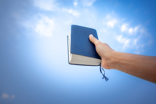 hand holding Bible, with the sky as the background in morning. copy space.
