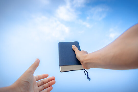 hand holding Bible, with the sky as the background in morning. copy space.