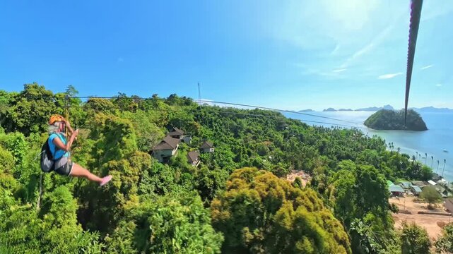 Tourists experiencing an exhilarating zipline adventure high above the lush green landscape of Las Cabanas Beach and the sparkling blue waters of Bacuit Bay in El Nido, Palawan island of Philippines