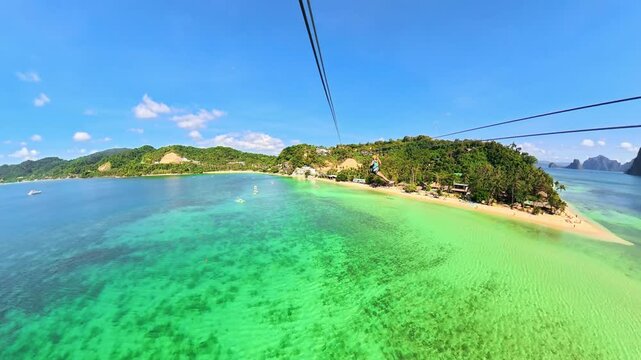 woman enjoying a zipline adventure high above the clear tropical waters and golden sand of Las Cabanas Beach and Bacuit Bay, surrounded by lush green islands in El Nido, Palawan island of Philippines