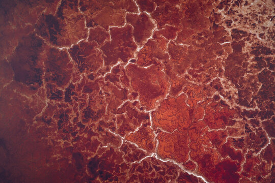 Aerial view of Searles Lake featuring vibrant red mineral deposits and white crystalline salt crust patterns San Bernardino County, California, United States.