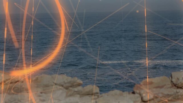 Rocky shoreline and sea receiving orange trails starting left, sweeping and showing coastal motion