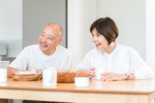 A smiling senior couple chatting with family while drinking coffee.