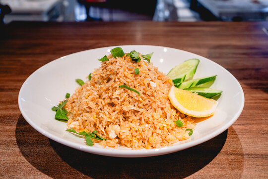 Egg fried rice with a side of cucumber slices and a lime wedge.