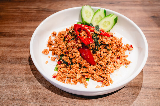 Stir-fried minced pork with holy basil served on a white plate.