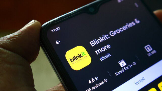 A person holding a smartphone with the Blinkit app on the screen