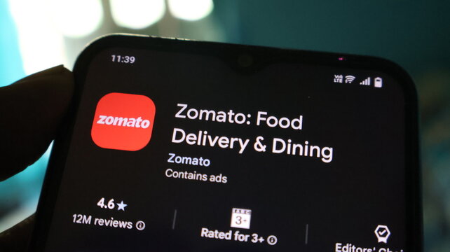 A hand holding a smartphone with the Zomato app open on the screen