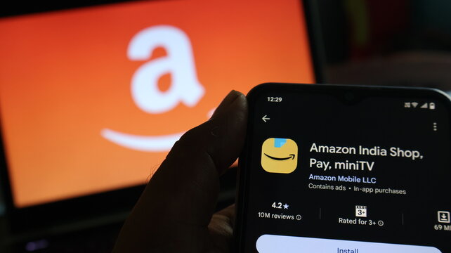 A hand holding a smartphone with the Amazon India app on screen