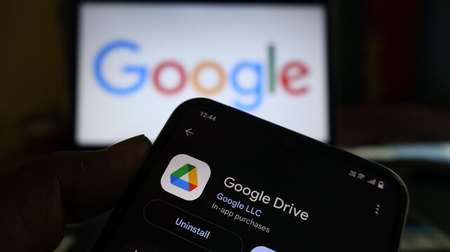 A smartphone displaying the Google Drive app in front of a Google logo on a screen