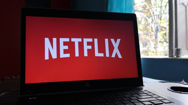 A laptop displaying the Netflix logo on its screen in a room