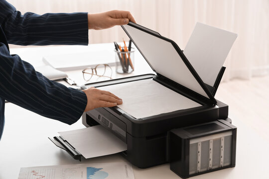 Businesswoman using printer on desk in office