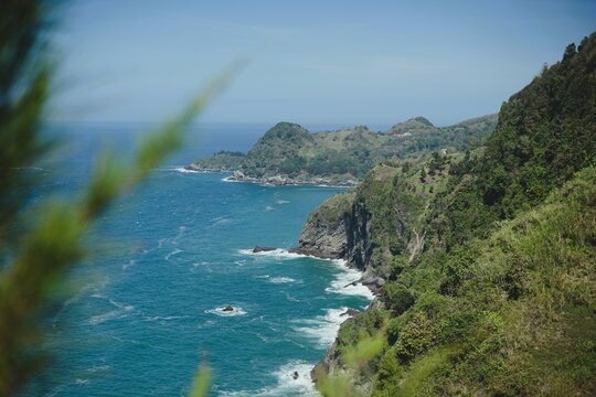 Scenic coastal landscape view from Bukit Jerit, Kebumen, Central Java, Indonesia. A beautiful panorama of green hills meeting the deep blue ocean with dramatic cliffs and clear tropical atmosphere.
