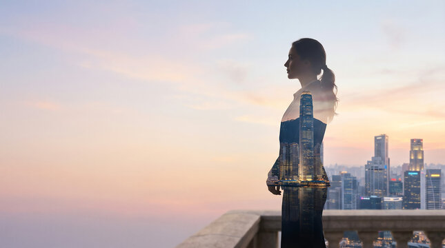 Silhouette of a businesswoman looking out over a city skyline at sunrise