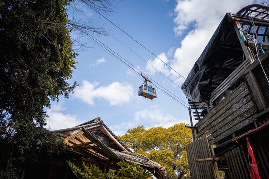 The Mt. Senkoji Ropeway cable car passes above rooftops on its way to the summit of Mt. Senkoji in Onomichi, Japan, overlooking the city and Seto Inland Sea.