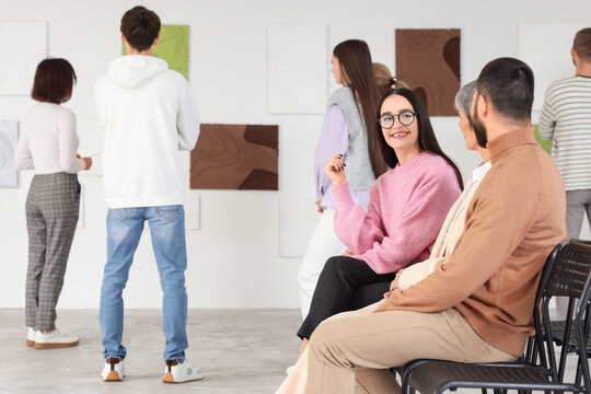 People sitting at exhibition in art gallery