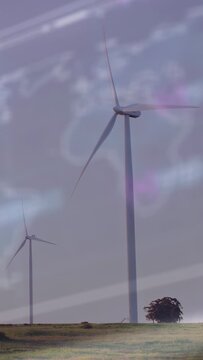 Vertical video: Steady wind driving turbine blades rotating slowly making power under purple haze