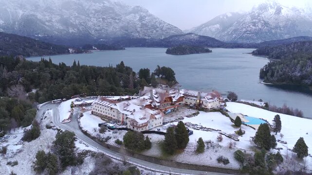 Llao Llao Peninsula between Moreno Lake and Brazo Campanario of Nahuel Huapi Lake with iconic hotel and resort, with Isla Fray Men&eacute;ndez and snowcapped Andean Patagonian fores, drone establishing shot