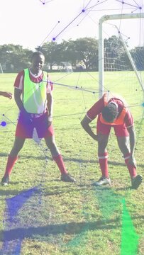 Vertical video: Soccer man neon bib taking stance after arm raise as purple overlay showing warm-up