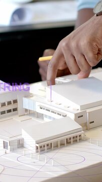 Vertical video: Designers tapping model roof, peer pointing, causing purple AR rings marking module