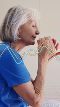 Vertical video: Senior woman lifting pink mug and inhaling, causing waves for health breathing