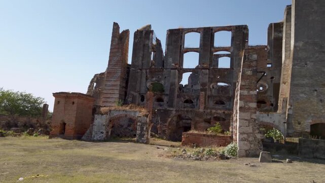 Abandoned hacienda ruins with broken walls and exposed arches, open yard in front, weathered brick structure showing decay, history and quiet rural environment