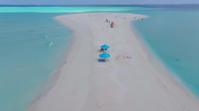 Beautiful aerial drone footage flying over a remote tropical sandbank surrounded by crystal clear turquoise waters near Vashafaru Island in northern Maldives.