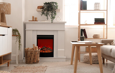 Naklejka premium Interior of living room with commode, shelving unit, coffee table, fireplace and firewood in wicker basket
