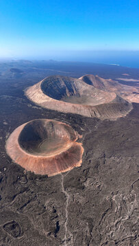 Aerial view of the impressive Caldera Blanca volcanic crater and surrounding lava fields under a clear blue sky in Las Palmas, Canary Islands, Spain.