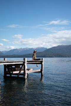 Chico en muelle de un Lago de la Patagonia Argentina al sol en con sombrero