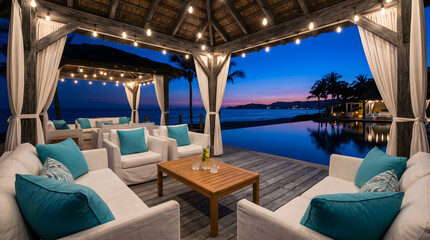 Fototapeta premium Luxury tropical resort outdoor lounge at twilight with white sofas, turquoise pillows, string lights, and an infinity pool overlooking the ocean.