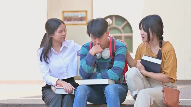 Supportive Asian female students comforting disappointed male classmate after failing exam