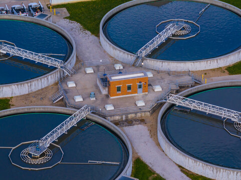 Aerial view of circular clarifier tanks and a central control building at a wastewater treatment facility with rotating bridges and blue water Indianapolis, Indiana, United States.